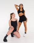 Young women wearing ribbed activewear black bodysuit & activewear black crop & shorts