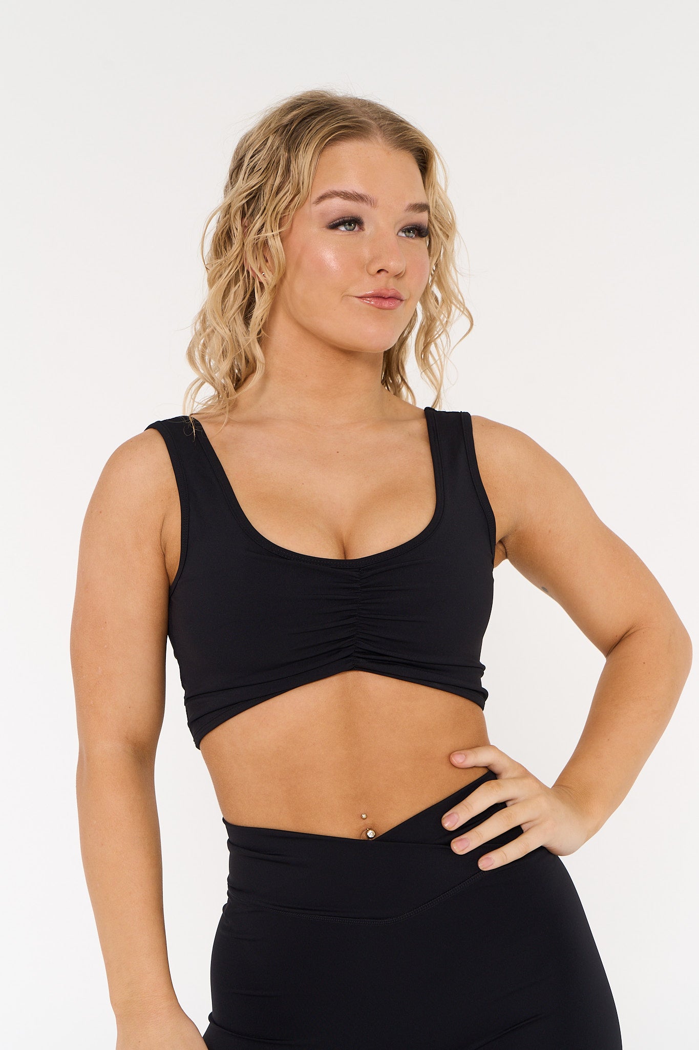 young woman wearing black low scoop activewear crop.