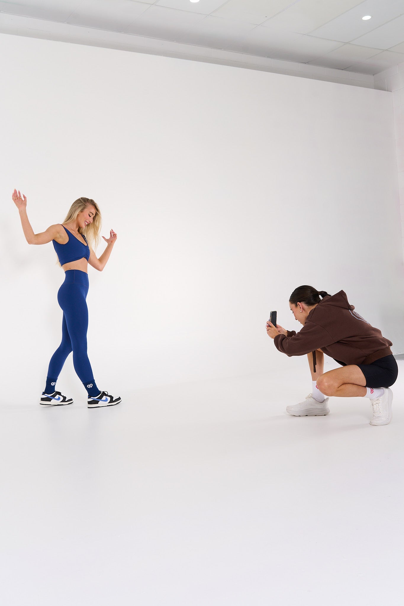 young woman getting photographed wearing navy high waisted activewear tights.