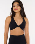 young woman wearing black twist knot activewear crop.