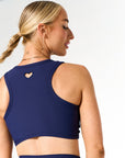 Young woman wearing Navy active wear heart top. 
