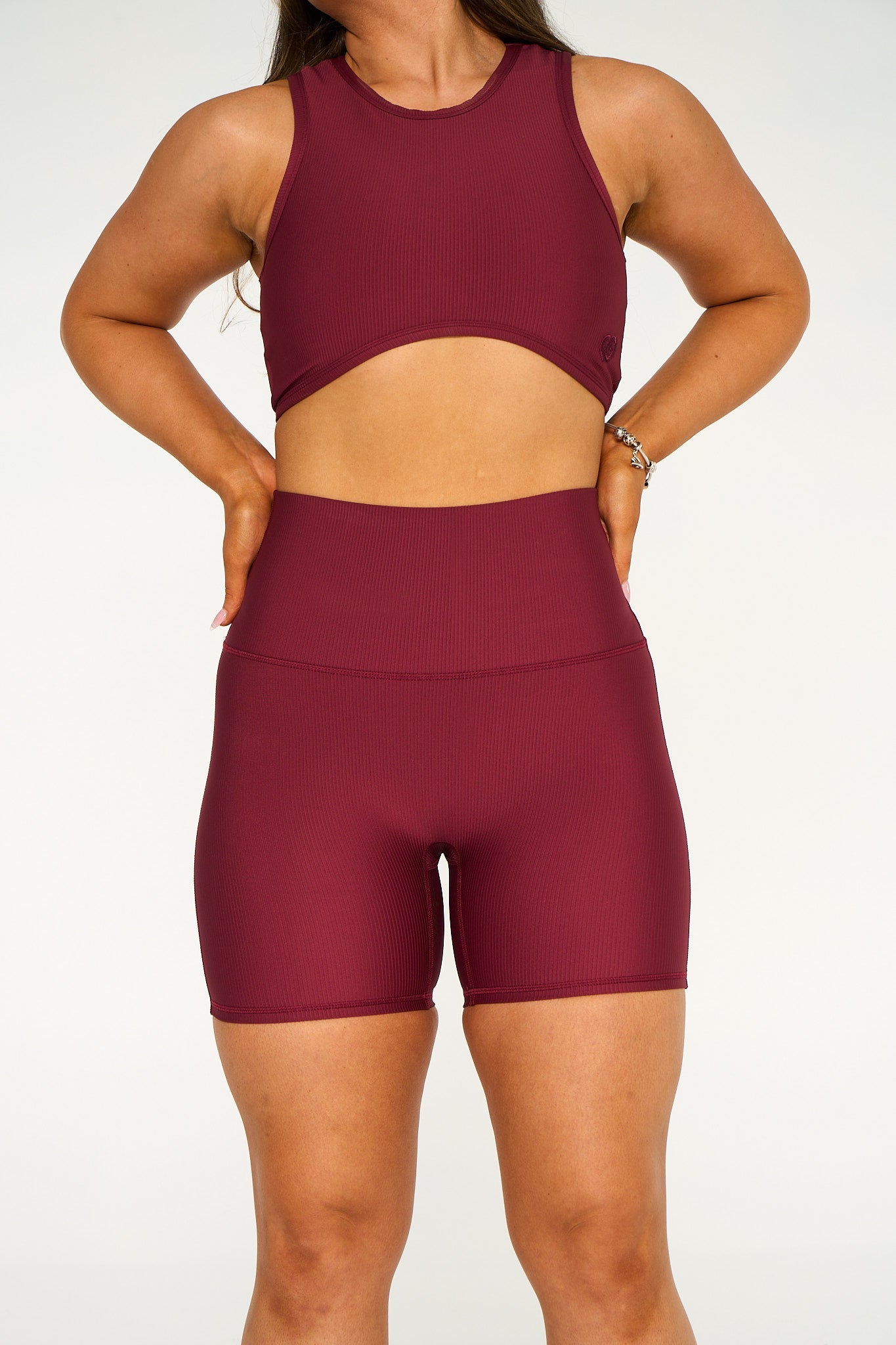 Young woman wearing deep red active wear high waisted bike shorts. 