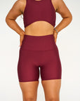 Young woman wearing deep red active wear high waisted bike shorts. 